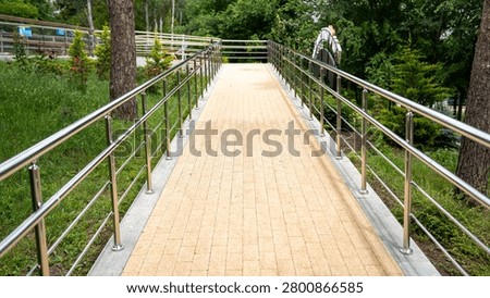 A well-maintained, accessible pathway lined with stainless steel railings, surrounded by lush greenery.