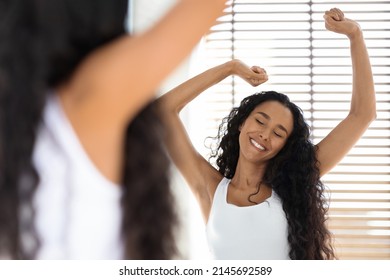 Wellness Concept. Portrait Of Beautiful Young Arab Lady Dancing Near Mirror In Bathroom, Happy Millennial Woman Stretching Hands And Smiling, Enjoying Relaxing Morning At Home, Selective Focus