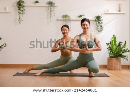 wellness Couple Asian young woman stand on toe and heel on yoga mat doing breathing and balancing exercise together.Smile Yoga meditation of two healthy female workout relax and comfort at cozy home