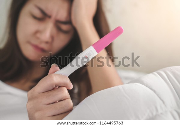 wellness and healthy concept, infertility\
problem,Unhappy young asian woman holding pregnancy test showing a\
negative result, Selective\
focus.