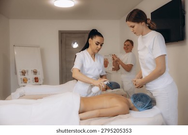 Wellness instructor demonstrating massage techniques and applying cream to a student during a professional spa training course in a bright room