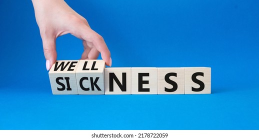 Wellness and Sickness symbol. Hand turns a cube and changes the word sickness to wellness. Beautiful blue background. Businessman hand. Business and wellness and sickness concept. Copy space