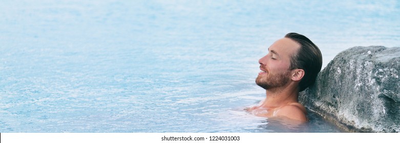 Wellness Spa Man Relaxing In Hot Springs Outdoor At Luxury Resort Spa Retreat. Handsome Young Male Model With Eyes Closed Resting In Natural Water Pool On Travel Vacation Holiday. Banner Background.