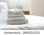 Wellness and spa relaxation, stack of clean white towels with tropical flowers on a hotel bed for hospitality and luxury lifestyle comfort