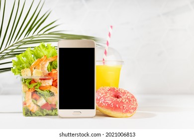 Wellness Summer Food Set Of Orange Juice, Pink Donut, Tropical Shrimp Salad In Box, Blank Phone In White Bar Interior, Palm Leaf. Concept Advertising For Restaurant Take Away Or Delivery Food Service.