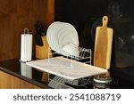 A well-organized kitchen countertop with a dish drying rack, paper towel holder, knife block, cutting board, and a marble-patterned drying mat