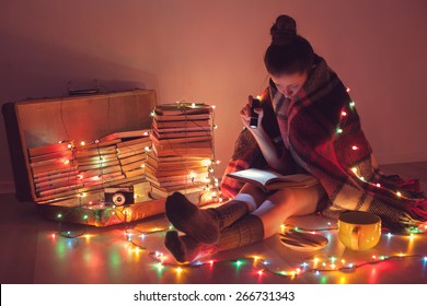 Well-read Girl At Home In Christmas Lights. Night Exciting Reading By Book Lover