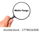 Wells Fargo on a white background view through a magnifying glass. Male hand holds a magnifying glass. 