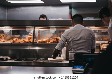 Wells-next-the-sea, UK - April 20, 2019: Staff serving fish and chips inside popular French's fish and chip shop in Wells-next-the-sea, a seaside town and port in Norfolk, UK, famous for its beach.