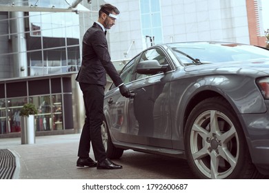 Well-trained Hotel Employee Wearing A Facial Shield And Disposable Gloves Opening A Car Door To Let A Person Out