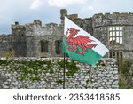 A Welsh flag with dragon symbol flying in front of an historic castle