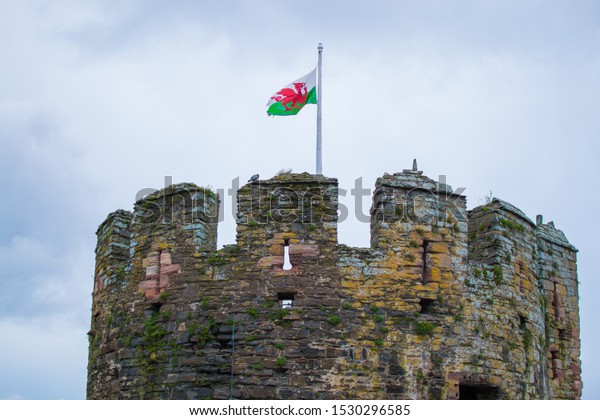 Welsh flag on\
the top of a tower of Conwy Castle, an ancient 13th Century stone\
built fortification in North\
Wales
