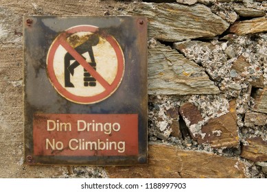 Welsh Language No Climbing Dim Dringo Sign On An Old Stone Wall With Symbol Of Man Climbing On A Wall In A Red Circle With Red Line Through