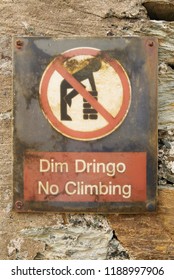 Welsh Language No Climbing Dim Dringo Sign On An Old Stone Wall With Symbol Of Man Climbing On A Wall In A Red Circle With Red Line Through