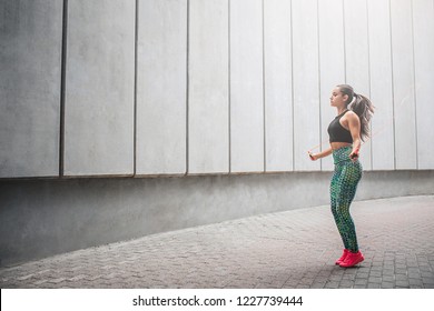 Wel-shaped young woman jumping with rope alone in corridor. She exercises very hard. Model has workout.