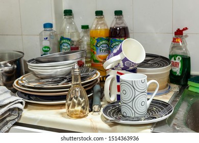 WELWYN GARDEN CITY, UK - SEPTEMBER 23, 2019: Dirty Plates And Cutlery On A Messy Kitchen Worktop