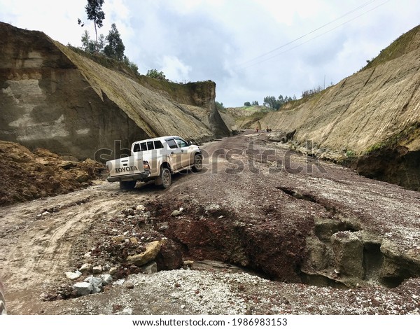 Wenchi, Ethiopia - 12 June 2019 : A\
pickup truck drives around an enormous pot hole in the\
road.