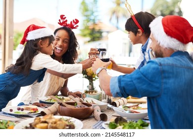 Were All Feeling The Holiday Spirit Today. Shot Of A Beautiful Young Family Sharing A Toast While Enjoying Christmas Lunch Together Outdoors.