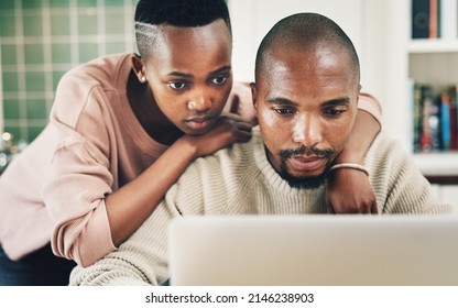 Were Both Serious Bloggers. Shot Of A Young Couple Using A Laptop While Relaxing Together At Home.