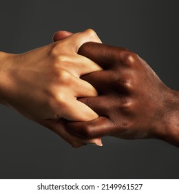 Were bound together forever. Studio shot of two unrecognizable people holding their hands together against a grey background.