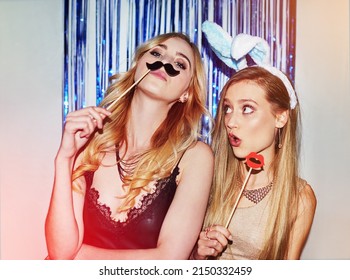 Were The Life Of The Party. Shot Of Two Beautiful Young Women Having Fun With Props In A Photobooth.