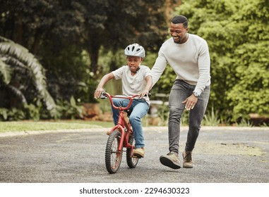 Were standing tall. Shot of an adorable boy learning to ride a bicycle with his father outdoors. - Shutterstock ID 2294630323