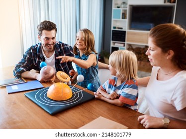 Were Travelling Through The Universe Together. Shot Of A Beautiful Young Family Working Together On A Science Project At Home.