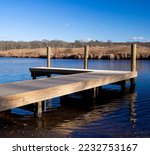 Wertheim National Wildlife Refuge, Long Island, New York. Wooden dock on Carmans River, blue sky and calm water on a winter day. The habitats of the refuge are a haven for many wildlife and birds.