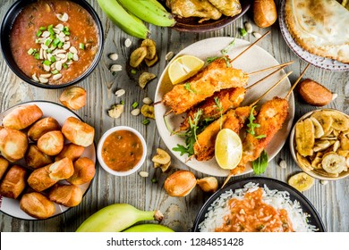 West African Food Concept. Traditional Wset African Dishes Assortment - Peanut Soup, Jollof Rice, Grilled Chicken Wings, Dry Fried Bananas Plantains, Nigerian Chicken Kebabs, Meat Pies, Top View