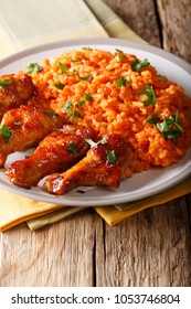 West African Food: Jollof Rice With Fried Chicken Wings Close-up On A Plate. Vertical
