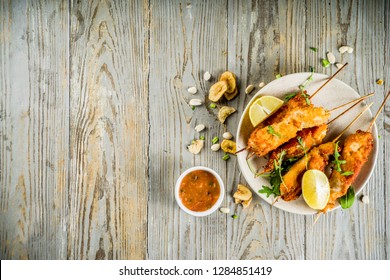 West African Food, Spicy Nigerian Chicken Kebabs With Peppered Sauce, Chin Chin And Dry Plantains, Wooden Background Copy Space Top View