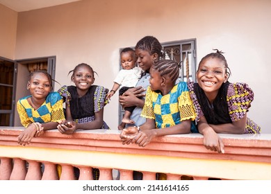 West African Mother holding cute little baby boy,surrounded by her four beautiful and cheerful daughters dressed up for celebration.