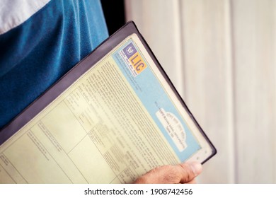 West Bengal, India, January 28, 2021 : Lic Stock Image Background. Person Or A Man Holding Life Insurance Corporation Of India Policy Plan Documents Or Papers In His Hand At Home.