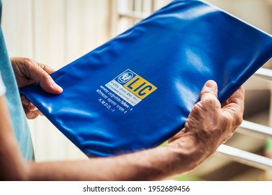 West Bengal, India, January 28, 2021 : Lic Background. Man Or A Senior Citizen Holding Life Insurance Corporation Of India Policy Plan Documents Or Paper In His Hand At Home.