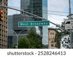 West Broadway street sign in a Manhattan featuring modern buildings and green trees on a clear day