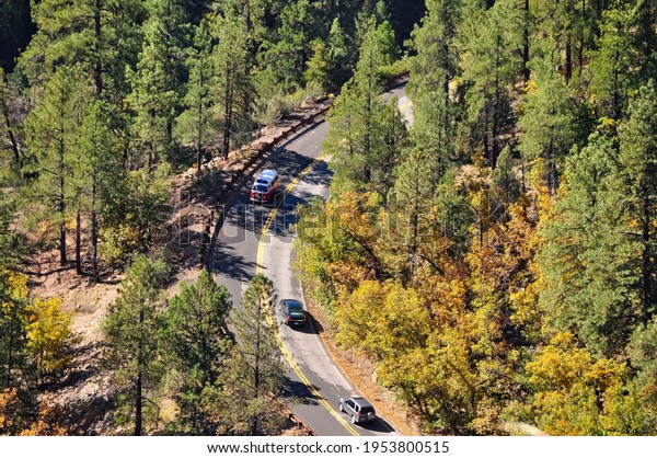 West Coast,\
USA-October 2020; Aerial view of a curve in the road in a\
mountaines area with trees with number of cars on the road amongst\
which a red and white classic camper\
van