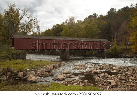West Cornwall Covered Bridge in Connecticut. Red wooden covered bridge on the river with current.