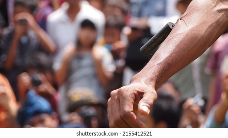 West Java, Indonesia - December 2, 2012 : close up of the hands of participants in a folk event showing off their immune system with a sharp object stabbing them