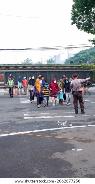 West\
Java, Indonesia, October 17, 2021. Officers help people cross the\
road to be safe and avoid collisions or\
accidents