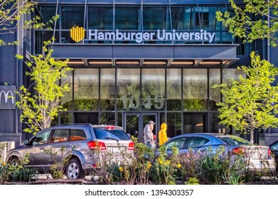 West Loop, Chicago-May 4, 2019: People Walk Past The Front Entrance To Hamburger University, McDonald's Headquarters Located On The Near West Side. Main Street In Chicago.