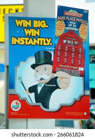 WEST PALM BEACH, FL - March 20, 2015: An Outdoor Sign Advertising The Monopoly Game In The Florida Lottery Showing The Iconic Monopoly Man On A Blue Background With A Red Hotel Behind Him