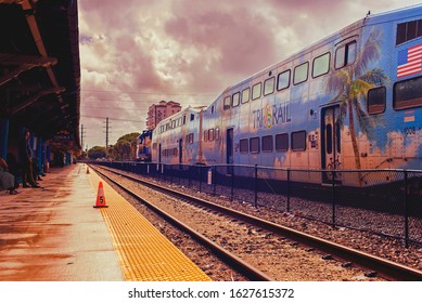 West Palm Beach FL USA 01/24/2020 Tri Rail Train On Far Tracks In Color On A Rainy Day With Passengers Waiting