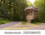 The west side of Mushroom Rock, a mushroom-shaped rock seen along the Little River Canyon Rim Parkway National Preserve in Alabama. The landmark sits between the two lanes of the scenic road.