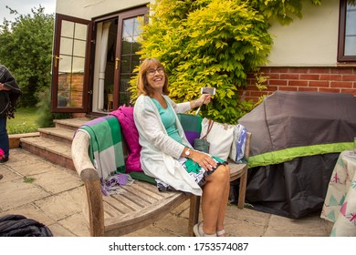 West Sussex, UK 9th June 2020
Mature Woman At Her First Non Zoom Book Club Meeting Since The Start Of Lockdown - Outside With Social Distancing