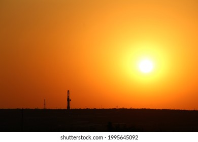 West Texas Desert Sunset With Two Drilling Rigs In The Far Distance