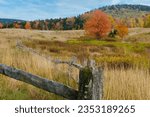 A West Virginia fall landscape along the highland scenic highway in Monongahela National Forest. A weathered wooden fence runs through the frame leading the eye to the mountains in the background.