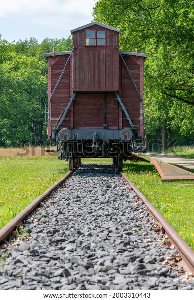 Westerbork, The Netherlands-July 2021; Low angle view\
along rail tracks towards a freight car used to transport and\
deport Jews and Gypsies from Transit Camp Westerbork to destruction\
camps during WW2