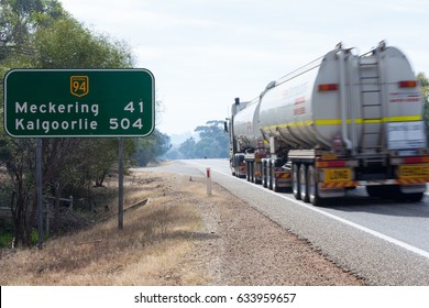 Western Australia / Australia – May 4th 2017: A B-Double tanker truck drives East toward Kalgoorlie along the Great Eastern Highway past the East bound sign indicating the distance to Kalgoorlie.
