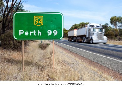 Western Australia / Australia – May 4th 2017: A B-Double truck drives East toward Kalgoorlie along the Great Eastern Highway past the West bound sign indicating the distance to Perth city.