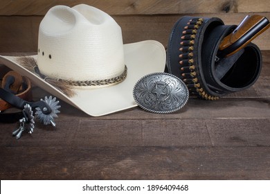 Western law: cowboy hat, spurs, belt buckle, six shooter and gun belt on old, worn wood.